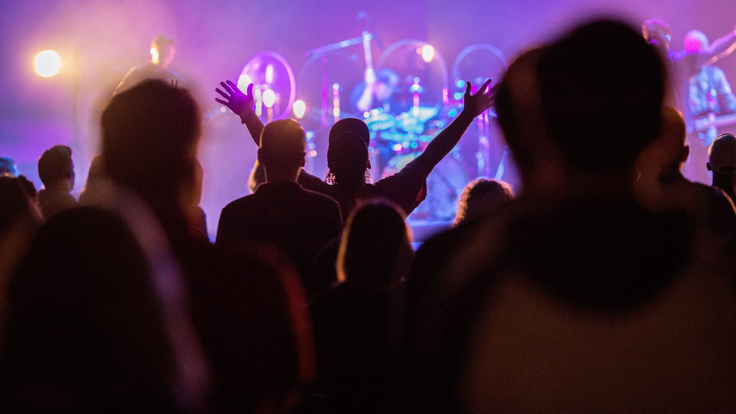 A group of people at a digital church concert with their hands raised on the church website.